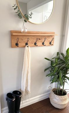 a potted plant sitting on top of a wooden floor next to a mirror and coat rack