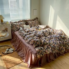 an unmade bed sitting on top of a hard wood floor next to a window