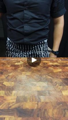 a man standing in front of a wooden cutting board