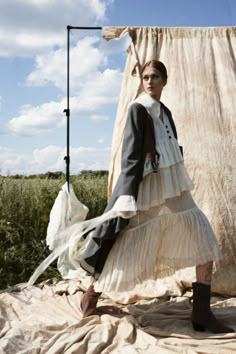 a woman in a dress and boots standing on a blanket with a backdrop behind her