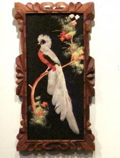 a painting hanging on the wall next to a wooden frame with a bird painted on it