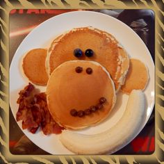 a plate with pancakes, bananas and some kind of monkey face