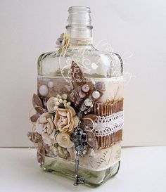 a bottle that has some flowers on it and is sitting next to a white wall