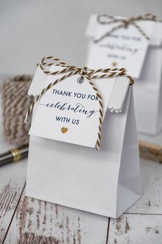 two small white bags tied with twine on top of a wooden table next to some brown and white twine