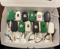 a box filled with green and white cupcakes in the shape of soccer balls