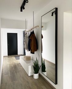 a coat rack and mirror in a room with wood flooring, white walls and wooden floors