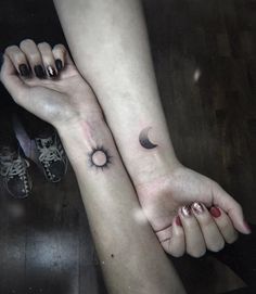 two people holding hands with tattoos on their arms and one has a crescent moon tattoo