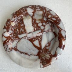 a marbled plate with brown and white designs on the top, sitting on a wall