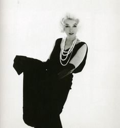 a black and white photo of a woman with pearls on her neck, in a dress