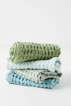 three folded blankets stacked on top of each other in different colors and patterns, one is green