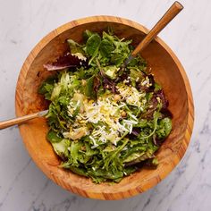 a salad in a wooden bowl with two serving utensils