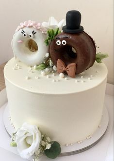 a white cake topped with two donuts and flowers