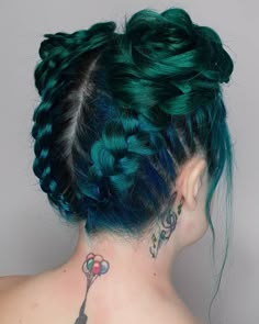 the back of a woman's head with green hair and tattoos on her neck