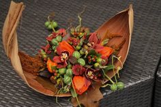 a bouquet of flowers on top of a wooden spoon sitting on a wicker table