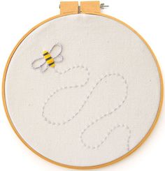 a bee is flying in the air on a white background with yellow and blue thread