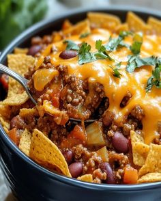 a bowl filled with chili, beans and tortilla chips on top of a table