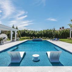 an empty pool with two lawn chairs next to it and a pergolated area in the background