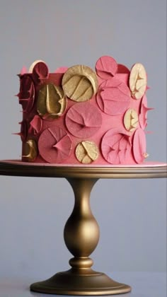 a pink and gold decorated cake sitting on top of a table