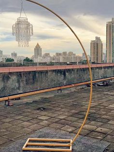 a wooden bench sitting on top of a brick floor next to a tall cityscape