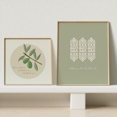 two framed art prints on a shelf next to each other, one with an olive branch