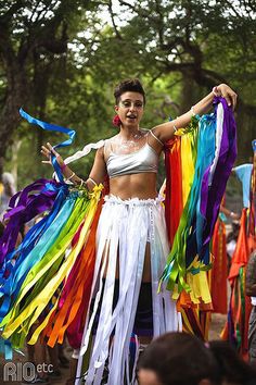 a woman in a white top and colorful streamers on her skirt at a parade