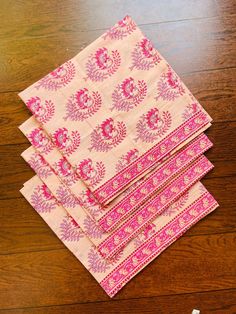 four pink and white napkins sitting on top of a wooden table