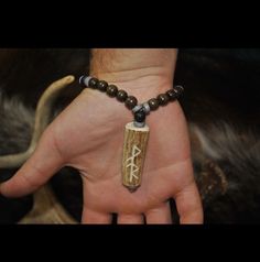 a person's hand with a beaded bracelet and an arrow charm on it