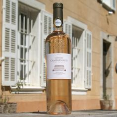 a bottle of wine sitting on top of a wooden table next to a brick building