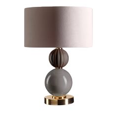 a table lamp with a white shade on it and a gold base around the lamp