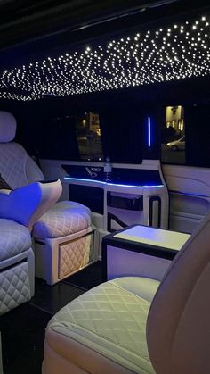 the interior of a luxury vehicle with white leather seats and lights on the ceiling above