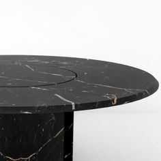 a black marble table with a circular design on it's top and two legs