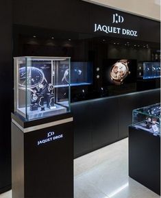 the inside of a jewelry store with watches in glass cases and lights on display behind them