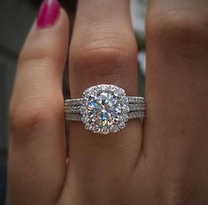 a woman's hand with a diamond ring on top of her finger and the other hand holding an engagement ring