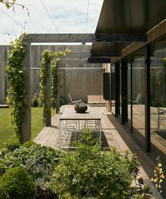 an outdoor dining area with table, chairs and potted plants on the decking