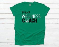 "Great tee shirt to promote your business. Perfect for distributors to wear while making shakes, serving shakes, during Weight Loss Challenges, passing out Invites, and other DMO's! The front of the shirt says, \"personal wellness coach.\" This is a great low cost promotional tool and a great way to advertise your club! Please check the size & color charts, not all colors are available in all styles." Herbalife Clothing, Personal Wellness, Nutrition Club, Coach Shirts, Herbalife Nutrition, Promotional Design, Wellness Coach, Business Person, Nutrition