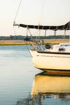 a sailboat floating on top of a body of water next to a shore line