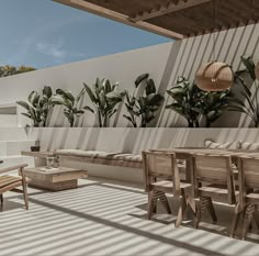 an outdoor living area with wooden furniture and potted plants on the wall, next to a terrace