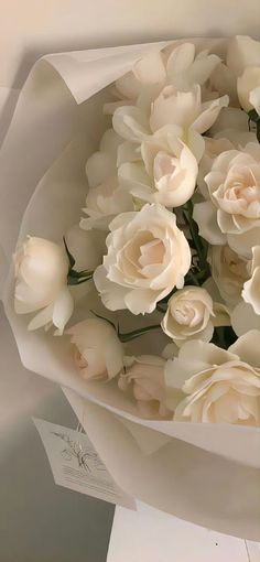 a bouquet of white roses is wrapped in paper and ready to be used as a gift