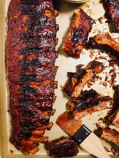 bbq ribs and barbecue sauce on a baking sheet with a spatula next to them