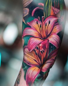 a tattoo with pink and yellow flowers on it's arm, in front of a blurry background