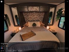 a bed in a trailer with pillows and blankets on it's headboard, next to two windows