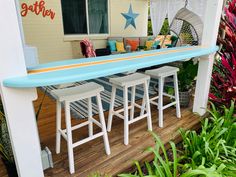 a blue surfboard sitting on top of a wooden deck next to a table and chairs