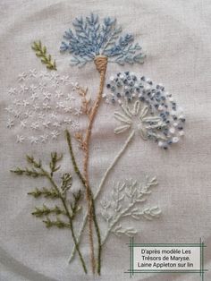 some flowers are on a white cloth with blue and green thread in the middle that is stitched together