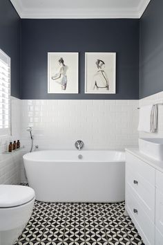 a white and black bathroom with two pictures on the wall