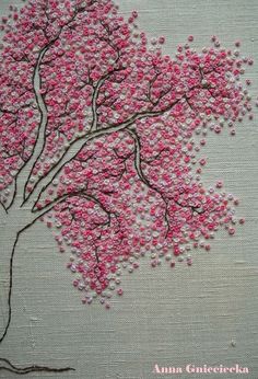 a tree with pink flowers on it is shown in the middle of an embroidered design