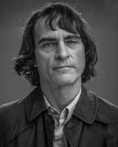 a black and white photo of a man with long hair wearing a shirt and tie