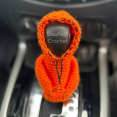 an orange knitted hoodie sitting in the center console of a car