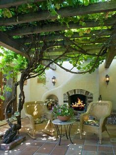 an outdoor living area with wicker furniture and fireplace