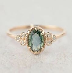 a ring with an oval shaped green stone surrounded by small white and yellow diamond accents