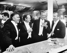 black and white photograph of men in tuxedos at bar